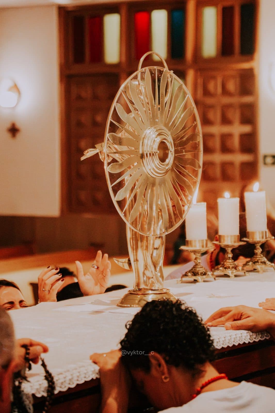 Verso do ostensório de Nossa Senhora das Graças sobre o altar, com os fiéis ao fundo